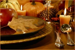 Photo of a place setting for dinner with apples, pumpkins, pinecones, leaves and candles