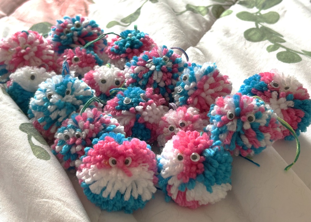 multiple yarn hugs with pink blue and white coloros with googly eyes in
