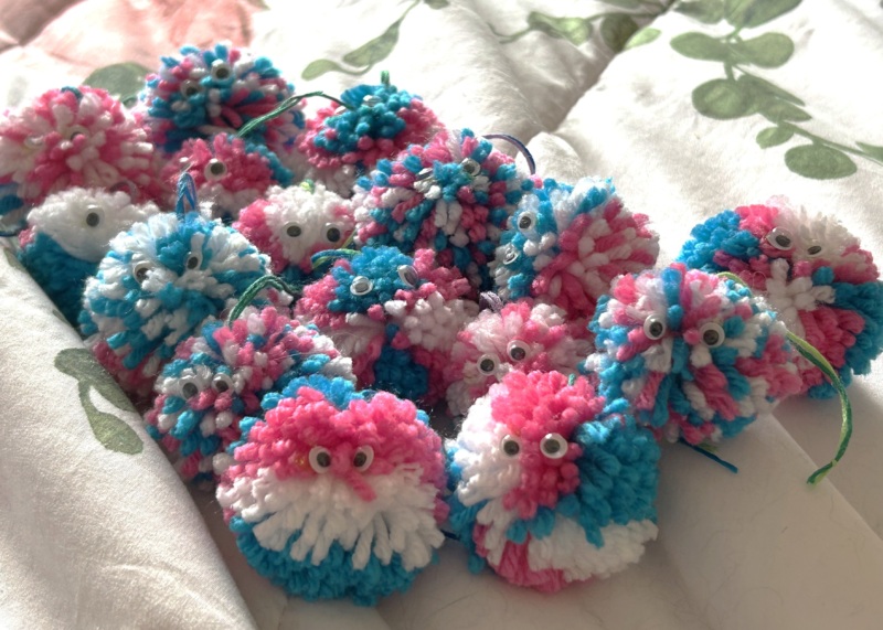 multiple yarn hugs with pink blue and white coloros with googly eyes in